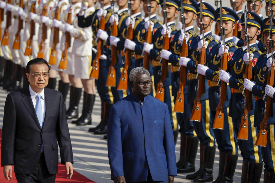 FILE - Chinese Premier Li Keqiang, left, and Solomon Islands Prime Minister Manasseh Sogavare review an honor guard during a welcome ceremony at the Great Hall of the People in Beijing, Wednesday, Oct. 9, 2019. Solomon Islands Prime Minister Sogavare has blamed foreign interference over his government's decision to switch alliances from Taiwan to Beijing for anti-government protests, arson and looting that have ravaged the capital in recent days. (AP Photo/Mark Schiefelbein, File)