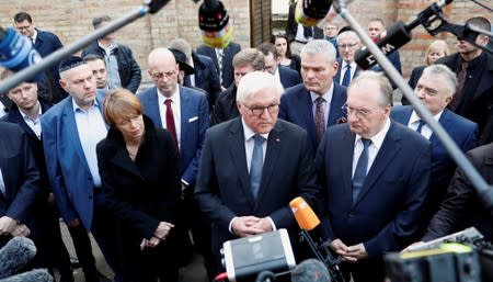 German President Frank-Walter Steinmeier speaks to the media next to his wife Elke Budenbender and Saxony-Anhalt State Premier Reiner Haseloff outside the synagogue in Halle