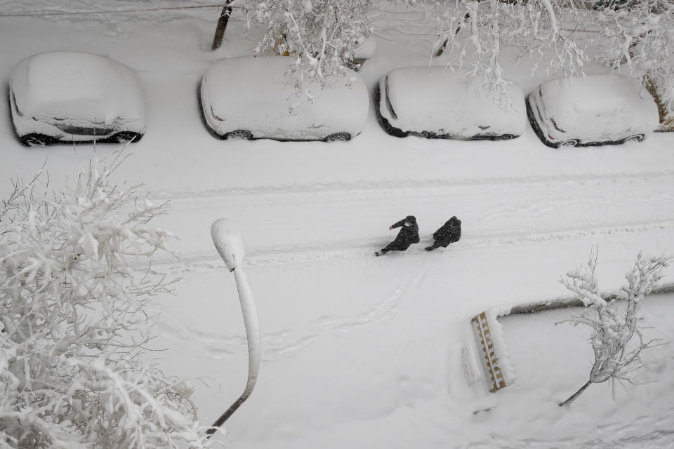 Dos hombres caminan por una calle cubierta de nieve tras una fuerte nevada, en Madrid, el 9 de enero de 2021. (AP Foto/Paul White)