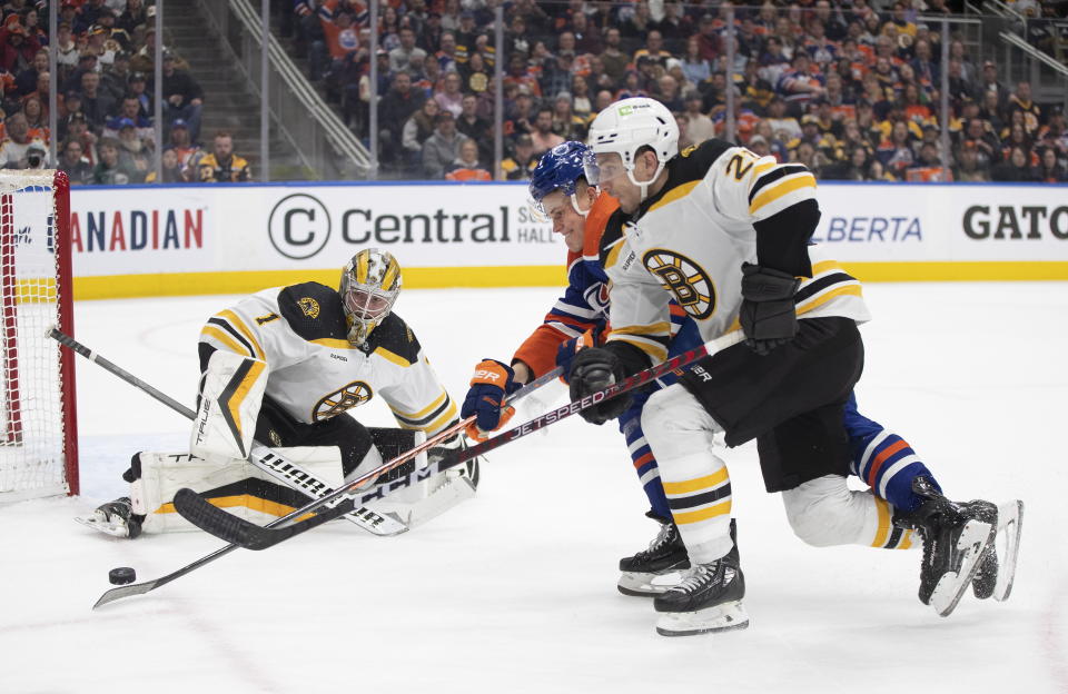 Boston Bruins goalie Jeremy Swayman (1) makes a save as Edmonton Oilers' Jesse Puljujarvi, center, and Bruins' Garnet Hathaway (21) battle for the rebound during second-period NHL hockey game action in Edmonton, Alberta, Monday, Feb. 27, 2023. (Jason Franson/The Canadian Press via AP)