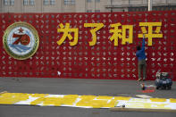 In this Saturday, Sept. 28, 2019, photo, a worker puts up the words "For Peace" for an exhibition on International Military Cooperation by the Chinese military to coincide with the 70th anniversary of the Founding of the People's Republic of China in Beijing. A parade on Tuesday, Oct. 1, 2019 by China’s secretive military will offer a rare look at its rapidly developing arsenal, including possibly a nuclear-armed missile that could reach the United States in 30 minutes, as Beijing gets closer to matching Washington and other powers in weapons technology. (AP Photo/Ng Han Guan)