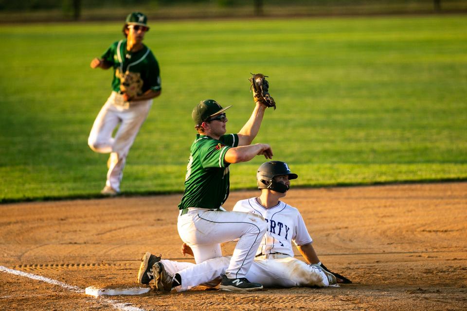 Iowa City West's Ryne Vander Leest holds up his glove after tagging out Iowa City Liberty's Luke Ramsey at third base during a high school baseball game, Friday, June 30, 2023, at Liberty High School in North Liberty, Iowa.