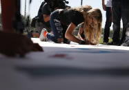 <p>Delany Tarr, a senior, signs a poster as she gathers together with some of her fellow students from Marjory Stoneman Douglas High School, where 17 classmates and teachers were killed during a mass shooting, after walking out of school during the National School Walkout on April 20, 2018 in Parkland, Fla. (Photo: Joe Raedle/Getty Images) </p>