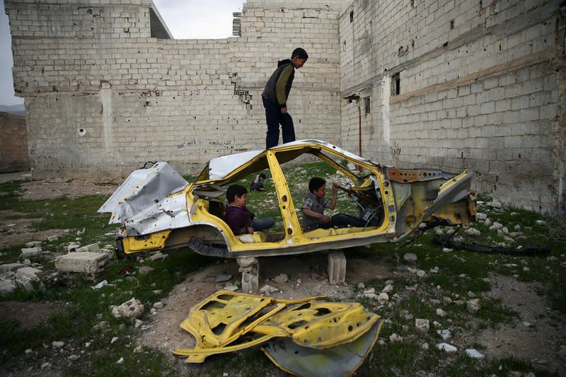 Boys play on a wrecked car in the rebel held besieged Douma neighbourhood of Damascus, Syria April 1, 2017. Picture taken April 1, 2017. REUTERS/Bassam Khabieh