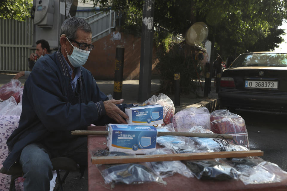 A street vendor wearing a mask to help stop the spread of the new coronavirus, sells face masks in Beirut, Lebanon, Monday, Jan. 4, 2021. Lebanon is gearing up for a new nationwide lockdown, as officials vowed Monday to take stricter measures against the coronavirus following the holiday season, which saw a large increase in infections and caused jitters in the country's already-battered health sector. (AP Photo/Bilal Hussein)