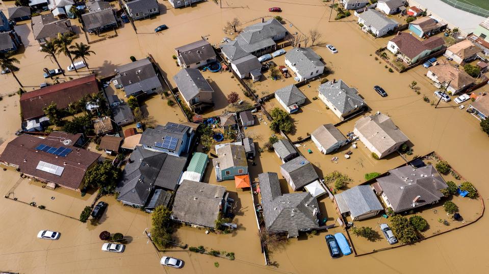 Floodwaters surround homes and vehicles in the community of Pajaro in Monterey County, Calif., on Monday, March 13, 2023. Built in the late 1940s to provide flood protection, the Pajaro River's levee has been a known risk for decades with several breaches in the 1990s. Emergency repairs to a section of the berm were undertaken in January.