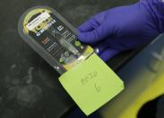 A researcher holds a Yolo! brand CBD vape oil cartridge and its packaging at Flora Research Laboratories in Grants Pass, Ore., on July 17, 2019. Authorities blamed Yolo for sending people to emergency rooms in Utah, saying it contained a dangerous synthetic marijuana. The cartridge pictured here was provided to The Associated Press by a South Carolina man who says he nearly died after puffing it. Testing commissioned by AP shows it contained the same synthetic marijuana that caused the illnesses in Utah. (AP Photo/Ted Warren)