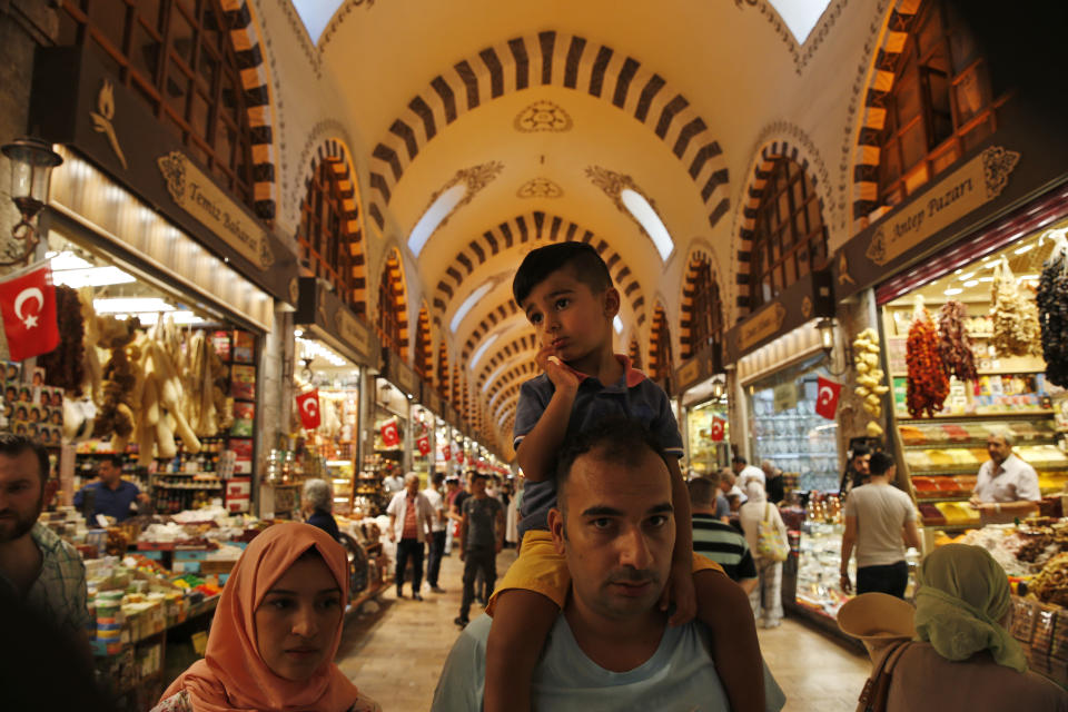 In this Monday, Aug. 20, 2018 photo, people walk in a covered market in Istanbul. Tourists have returned in droves to Turkey according to the government figures, helped this summer by the sharp fall in the value of the Turkish lira following economic uncertainty and a rift with the United States. (AP Photo/Lefteris Pitarakis)