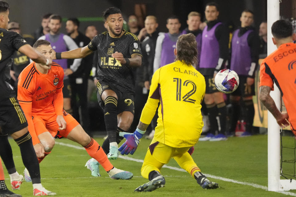 A shot from Los Angeles FC forward Denis Bouanga, center, is blocked by Houston Dynamo goalkeeper Steve Clark (12) during the second half in the MLS playoff Western Conference final soccer match Saturday, Dec. 2, 2023, in Los Angeles. (AP Photo/Marcio Jose Sanchez)