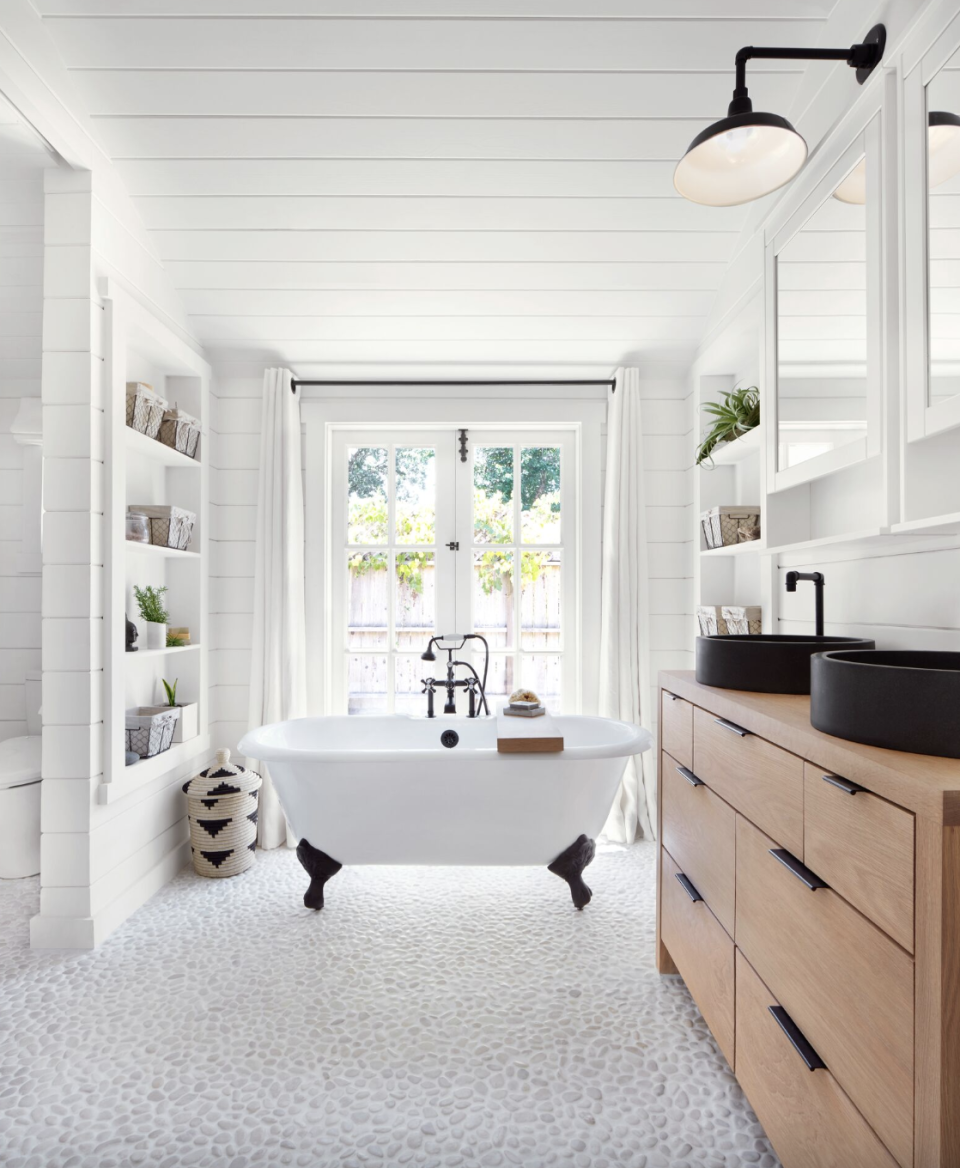 bathroom storage ideas, built in open shelves on both sides of a large white bathroom with a tub in the center