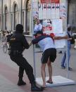 A Belarusian police officer detains a man in Minsk, Belarus, Saturday, Aug. 8, 2020. On Saturday evening, police arrested at least 10 people as hundreds of opposition supporters drove through the center of the capital waving flags and brandishing clenched-fist victory signs from the vehicles' windows. The presidential election in Belarus is scheduled for August 9, 2020. (AP Photo/Sergei Grits)