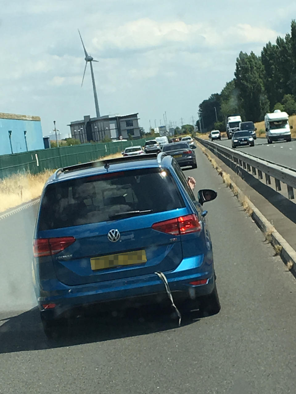 A delivery driver has revealed pictures of the moment a woman appeared to drive down a motorway with her foot hanging out of the window. Photo: Caters