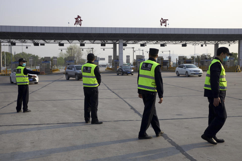 Security personnel wearing face masks to protect against the spread of new coronavirus direct vehicles entering Wuhan city at a toll gate in Wuhan in central China's Hubei Province, Wednesday, April 8, 2020. After 11 weeks of lockdown, the first train departed Wednesday morning from a re-opened Wuhan, the origin point for the coronavirus pandemic, as residents once again were allowed to travel in and out of the sprawling central Chinese city. (AP Photo/Ng Han Guan)