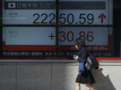 A woman walks past an electronic stock board showing Japan's Nikkei 225 index at a securities firm Wednesday, Aug. 22, 2018, in Tokyo. Asian shares were mixed Wednesday, as some markets were cheered by bullish sentiments on Wall Street despite concerns about an ongoing trade dispute with China. (AP Photo/Eugene Hoshiko)