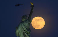 À New York, la statue de la Liberté a fait face à une splendide lune rousse. (Photo by Johannes EISELE / AFP)