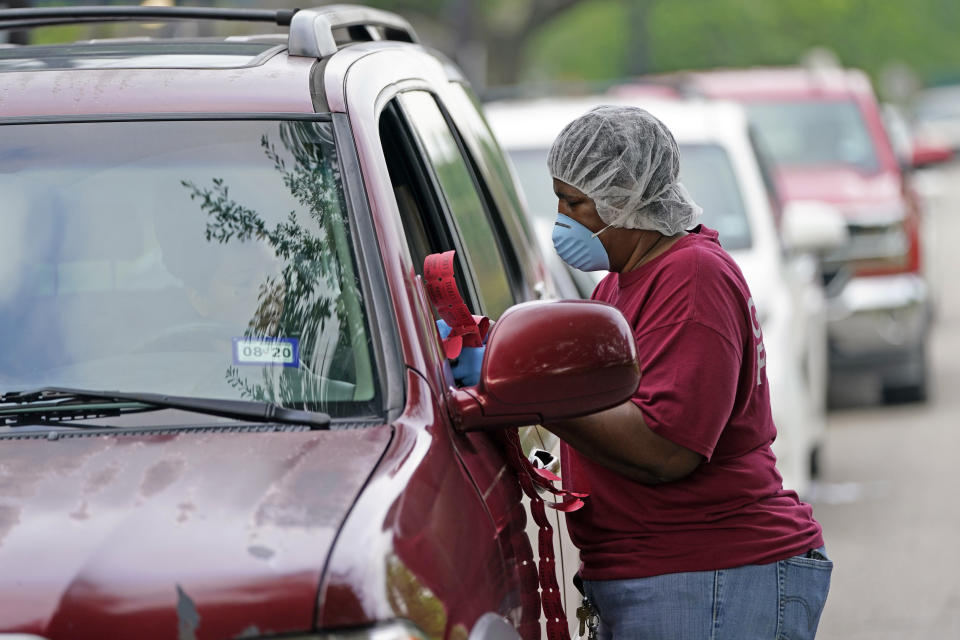 Monica Garrett, with Houston Independent School District Nutrition Services, collects information from people in line for food distribution Monday, April 6, 2020, in Houston. HISD relaunched their food distribution efforts throughout the district Monday, with a streamlined process that will implement increased safety measures. (AP Photo/David J. Phillip)