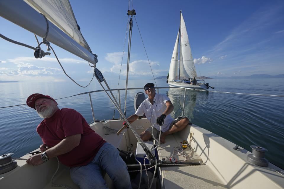 Bob Derby, right, and Randy Atkin, left, adjust sails to turn their boat through the Great Salt Lake on June 14, 2023, near Magna, Utah. Sailors back out on the water are rejoicing after a snowy winter provided temporary reprieve. (AP Photo/Rick Bowmer)