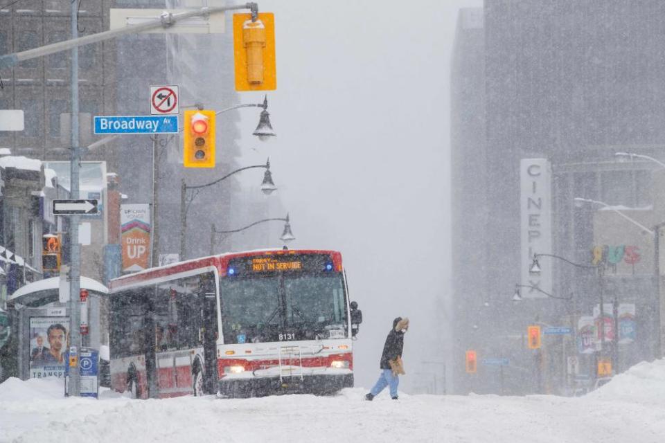 A pedestrian crosses the street as a city bus is pictured stuck during a winter storm in Toronto, Ontario, Canada.