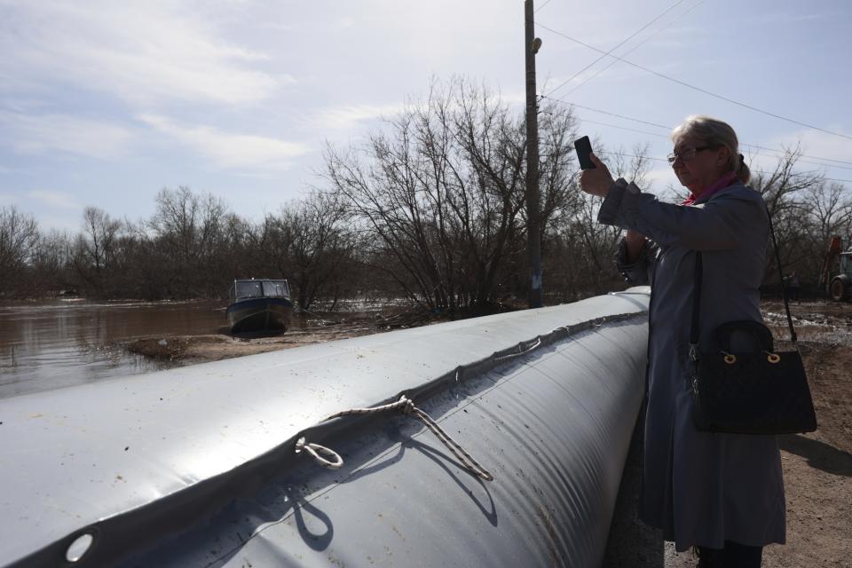 A woman takes a photo standing behind a rubber dam at a flooded area in Orenburg, Russia, on Thursday, April 11, 2024. Russian officials are scrambling to help homeowners displaced by floods, as water levels have risen in the Ural River. The river's water level in the city of Orenburg was above 10 meters (33 feet) Wednesday, state news agency Ria Novosti reported, citing the regional governor. (AP Photo)