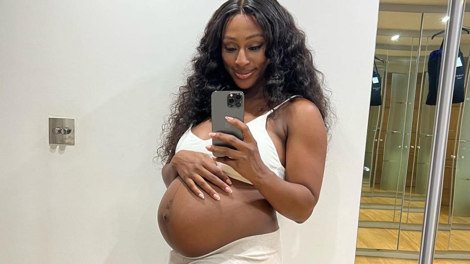 Alexandra Burke cradling baby bump