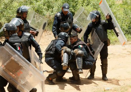 Riot police officers help an injured colleague during clashes with protesters from the National Coordination of Education Workers (CNTE) teachers’ union during a protest against President Enrique Pena Nieto's education reform, in the town of Nochixtlan, northwest of the state capital, Oaxaca City, Mexico June 19, 2016. REUTERS/Jorge Luis Plata