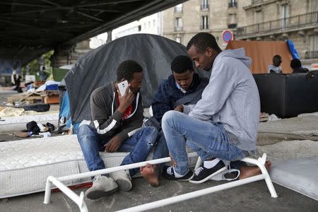 Migrants from Eritrea sit near tents as they live in a make-shift camp under a metro bridge in Paris, France, May 28, 2015. REUTERS/Benoit Tessier