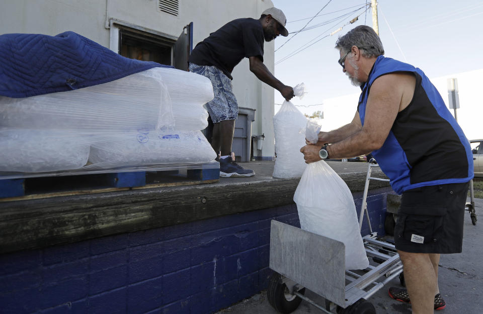 FILE - In this Sept. 19, 2018, file photo, Stan Atamanchuk, right, buys large bags of ice from Rose Ice & Coal days after Hurricane Florence in Wilmington, N.C. Many in Wilmington woke up Wednesday suddenly very tired. The days-long scavenger hunt for gas and ice was over as stores opened and relief agencies were able to roll into the city. (AP Photo/Chuck Burton, File)