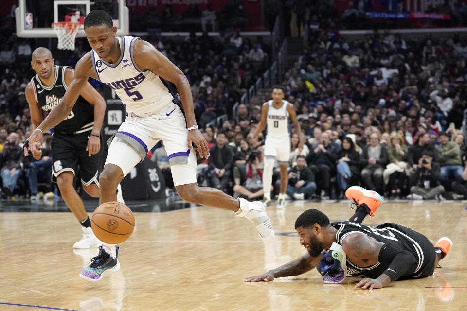 Sacramento Kings guard De'Aaron Fox, center, loses his shoe as he takes a loose ball away from Los Angeles Clippers forward Paul George, right, during the second half of an NBA basketball game Friday, Feb. 24, 2023, in Los Angeles. (AP Photo/Mark J. Terrill)