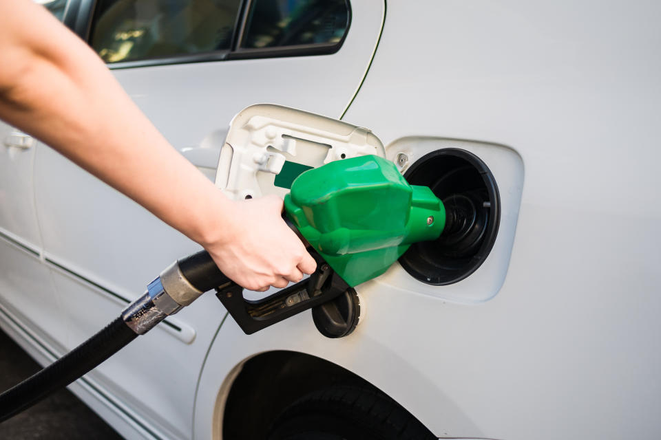 Hand holding a green diesel pump up to a car.