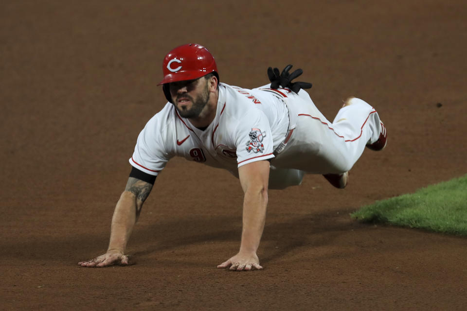 Cincinnati Reds' Mike Moustakas slides safely into third base as he advances on a fly ball for an out hit by Tyler Stephenson in the fourth inning during a baseball game against the Milwaukee Brewers in Cincinnati, Tuesday, Sept. 22, 2020. (AP Photo/Aaron Doster)