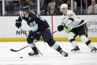 Seattle Kraken defenseman Vince Dunn (29) skates with the puck while under pressure from Los Angeles Kings center Rasmus Kupari (89) during the first period of an NHL hockey game, Saturday, April 1, 2023, in Seattle. (AP Photo/John Froschauer)