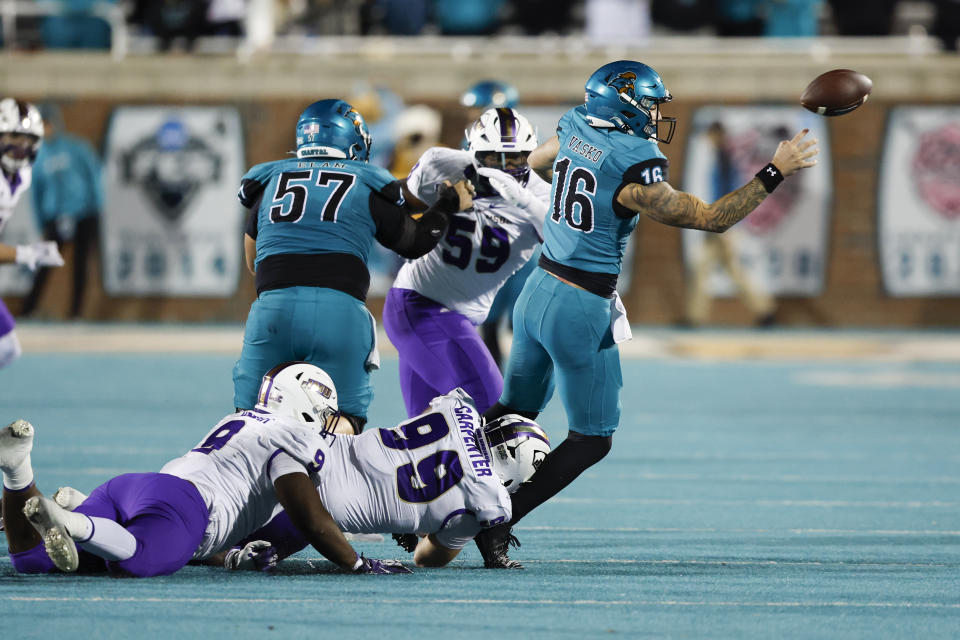 Coastal Carolina quarterback Ethan Vasko (16) passes as he is tackled by James Madison defensive lineman James Carpenter during the second half of an NCAA college football game in Conway, N.C., Saturday, Nov. 25, 2023. (AP Photo/Nell Redmond)