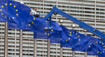 FILE - In this Wednesday, June 22, 2016 file photo, a worker on a lift adjusts the EU flags in front of EU headquarters in Brussels. Five years ago, Britons voted in a referendum that was meant to bring certainty to the U.K.’s fraught relationship with its European neigbors. Voters’ decision on June 23, 2016 was narrow but clear: By 52 percent to 48 percent, they chose to leave the European Union. It took over four years to actually make the break. The former partners are still bickering, like many divorced couples, over money and trust. (AP Photo/Virginia Mayo, File)