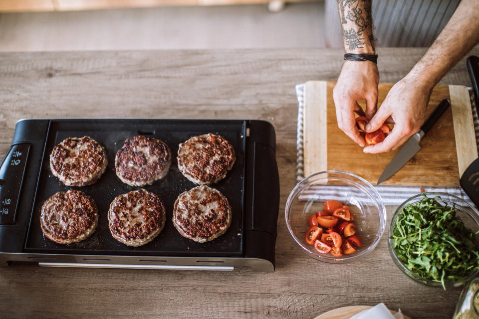 Male Chef Making Fresh Ripe Tomato Salad While Baking Homemade Hamburgers