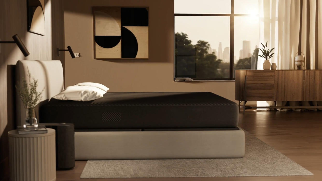  The Eight Sleep Pod 4 on a mattress in a bedroom with the Pod 4 hub next to the bed. 