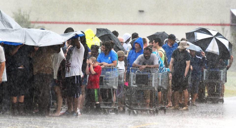 Customers waiting in line at the local grocery store get pelted during a deluge from Tropical Storm Florence in southeastern North Carolina on Sunday, September 16, 2018 in Rocky Point, N.C.