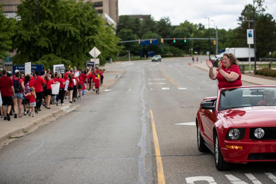 Renee Curtis, president of the Michigan Nurse Association-University of Michigan Professional Nurse Council (MNA-UMPNC), right, waves as nurses and their supporters march around hospital buildings during a July 16, 2022 picket at Fuller Park in Ann Arbor.