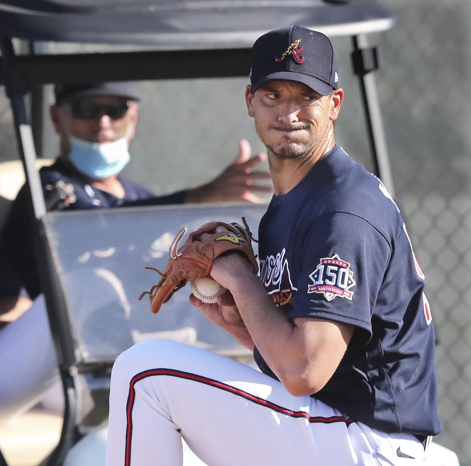 Atlanta Braves manager Brian Snitker, left, sits in a golf cart watching pitcher Charlie Morton get in some work during a morning pitching session on the practice mounds during baseball spring training at CoolToday Park in North Port, Fla., Friday, Feb. 26, 2021. (Curtis Compton/Atlanta Journal-Constitution via AP)