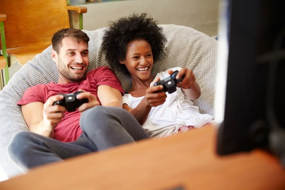 Smiling young man and woman playing video games