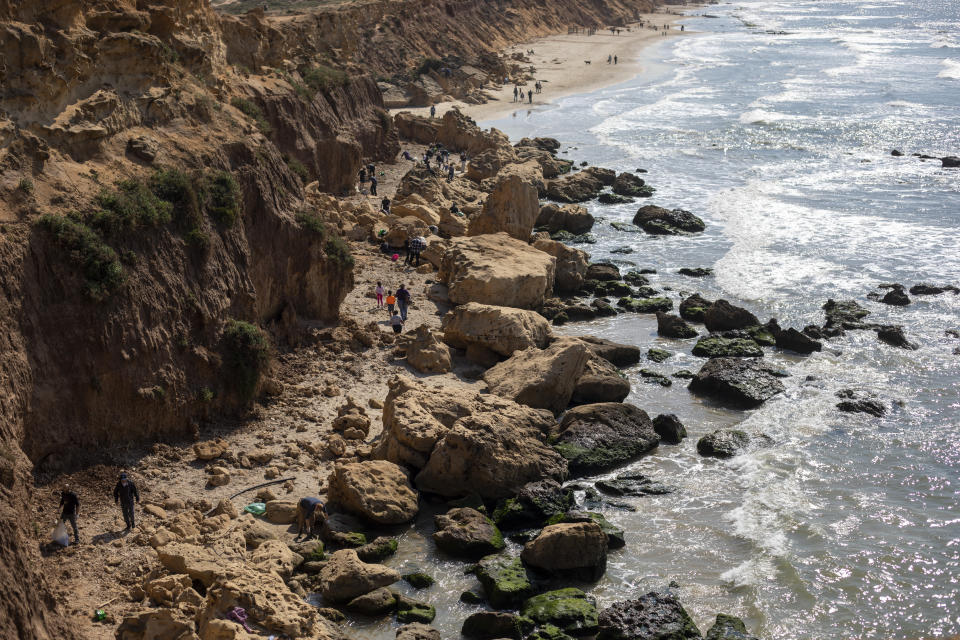 People clean tar from an oil spill in the Mediterranean sea in Gador nature reserve near Hadera, Israel, Saturday, Feb. 20, 2021. Hundreds of volunteers are taking part in a cleanup operation of Israeli shoreline as investigations are underway to determine the cause of an oil spill that threatens the beach and wildlife, at Gador Nature Reserve near the northern city of Hadera, the tar smeared fish, turtles, and other sea creatures. (AP Photo/Ariel Schalit)