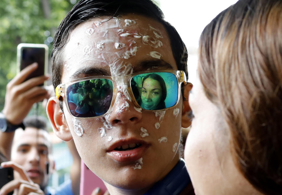 16-year-old Rufo Chacon, wearing reflective sunglasses, looks over at his mother Adriana Parada as they are met by a group of reporters outside the offices of Foro Penal, a Venezuelan human rights organization, in Caracas, Venezuela, Friday, July 19, 2019. The Venezuelan teenager who lost his eyesight when he was hit by police buckshot during a protest says he wants to continue studying. (AP Photo/Ariana Cubillos)