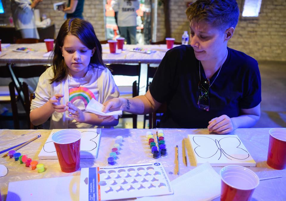 Sasha Hudgens and their daughter Catherine Hudgens, 10, paint on a butterfly canvas at the Day of Remembrance event for the March 2021 flood at Plaza Mariachi in the Xenote event room in Nashville, Tenn., Saturday, March 26, 2022. Hudgens was one of the survivors of the flood. 