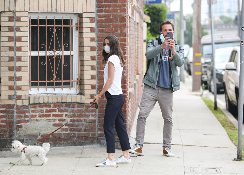 Ana taking her dog for a walk, while Ben uses his phone to take a picture of whoever is photographing them