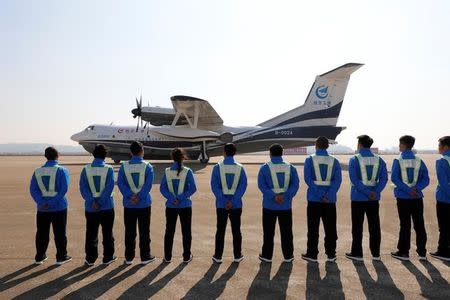 Members of ground staff stand in front of China's domestically developed AG600, the world's largest amphibious aircraft, after it lands on its maiden flight in Zhuhai, Guangdong province, China December 24, 2017. REUTERS/Stringer