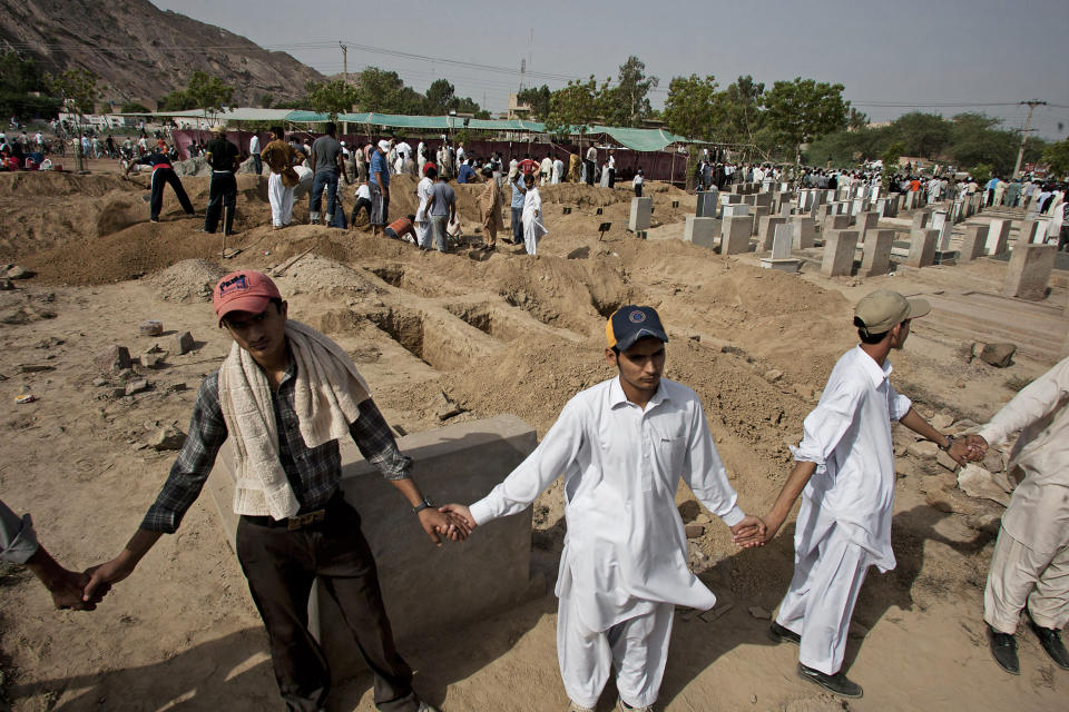 FILE - In this May 29, 2010 file photo, people from a minority Muslim Ahmadi Community stand guard as others preparing to bury the victims of attack by Islamic militants, in Rubwah, some 150 kilometers (93 miles) northwest from Lahore Pakistan. The U.S. Commission on International Religious Freedom on Friday, Jan. 8, 2021, adopted 55-year-old Ramazan Bibi, jailed on blasphemy charges in Pakistan, as a prisoner of conscience. According to a December report by the U.S. Commission for International Religious Freedoms, Pakistan recorded the most cases of blasphemy in the world even though 84 countries have criminal blasphemy laws on their books. (AP Photo/Anjum Naveed, File)