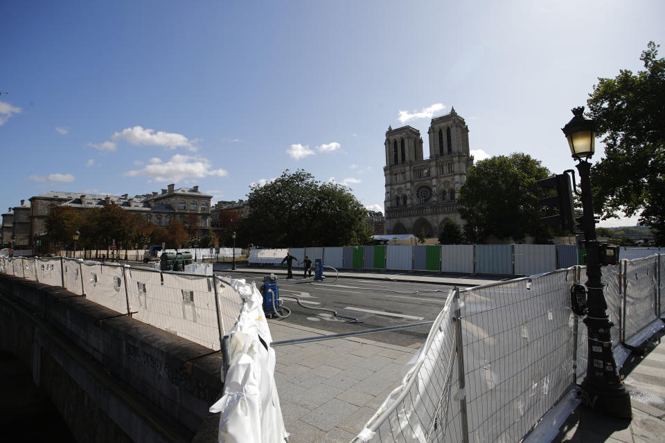 Workers prepare to clean the area around Notre Dame cathedral, Monday, Aug. 19, 2019 in Paris. Specialists shoring up fire-damaged Notre Dame Cathedral were returning to the Paris site on Monday for the first time in nearly a month, this time wearing disposable underwear and other protective gear after a delay prompted by fears of lead contamination. (AP Photo/Francois Mori)