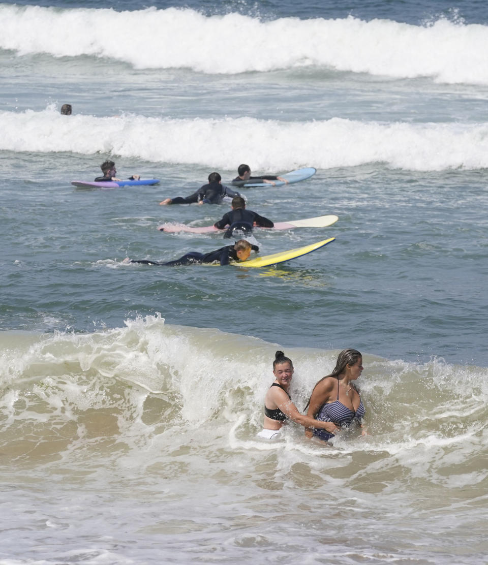 People in the sea off the beach at Saltburn-by-the-Sea, England, Thursday July 22, 2021. A heatwave which has baked the UK over the last few days is expected to end with thunderstorms across much of England and Wales over the next weekend, forecasters have warned. (Owen Humphreys/PA via AP)