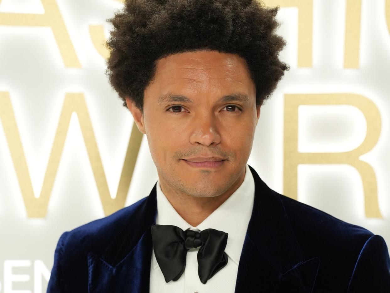 Trevor Noah poses for photos in a blue velvet suit and black bow tie.