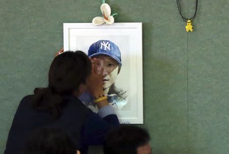 A family member of a missing passenger onboard the sunken ferry Sewol, touches her son's portrait as she cries at a gym in Jindo November 11, 2014. REUTERS/Park Cheol-hong/Yonhap