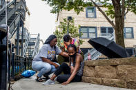 Jalisa Ford sits on the ground while rubbing the walkway where her 9-year-old son Janari Ricks was fatally shot while playing with friends at the Cabrini Green townhomes Saturday Aug. 1, 2020 in Chicago. A suspect has been arrested in the fatal shooting of the 9-year-old boy and police hope to secure charges against him in the coming days, the city's police superintendent said Monday, Aug. 3, 2020. (Armando L. Sanchez/Chicago Tribune via AP)